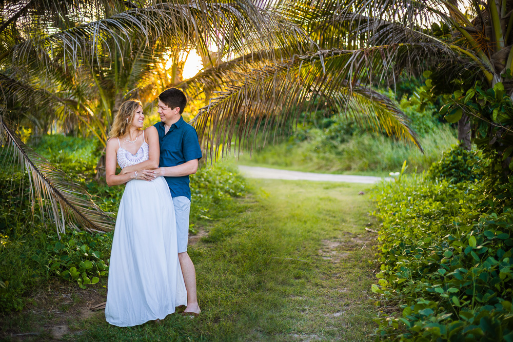 A bride in a lovely wedding dress smiles at her groom during their tropical elopement