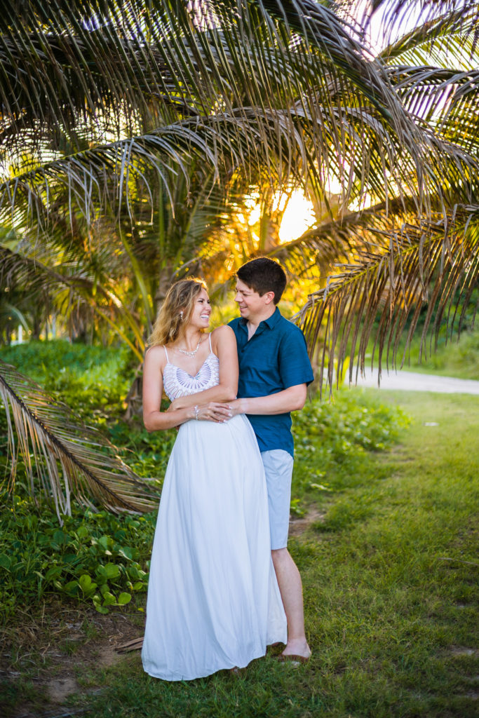 A bride in a lovely wedding dress smiles at her groom during their tropical elopement