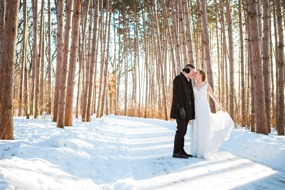 A couple dances among the tall pines during their winter elopement