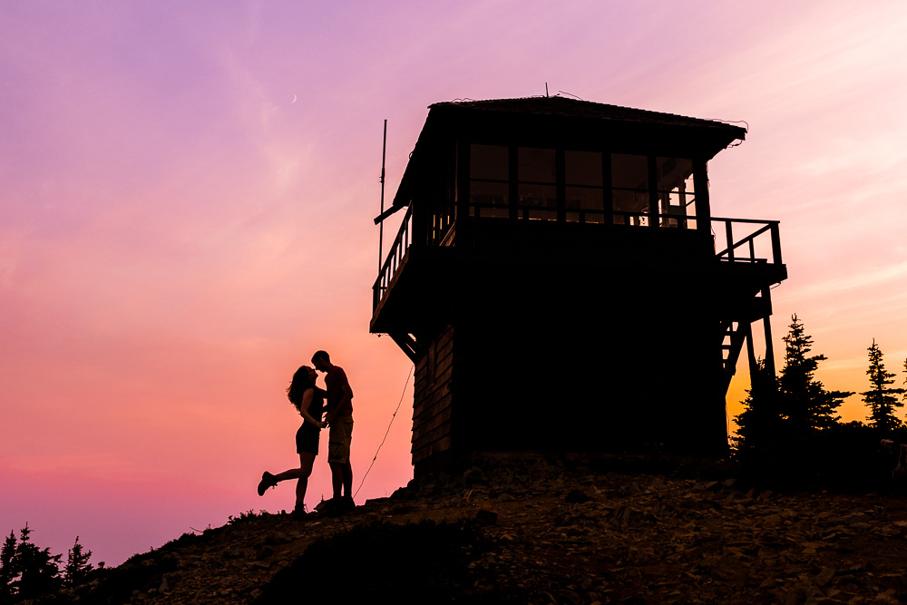 A silhouette of a couple next to a fire tower with a beautiful sunset background. A perfect place to elope!