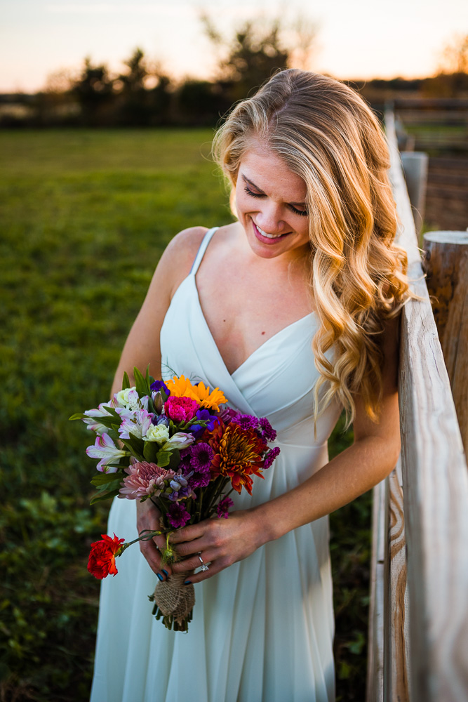 A beautiful bride in a simple white wedding dress holds a colorful flower bouquet. Fall is a beautiful time to elope in Minnesota!