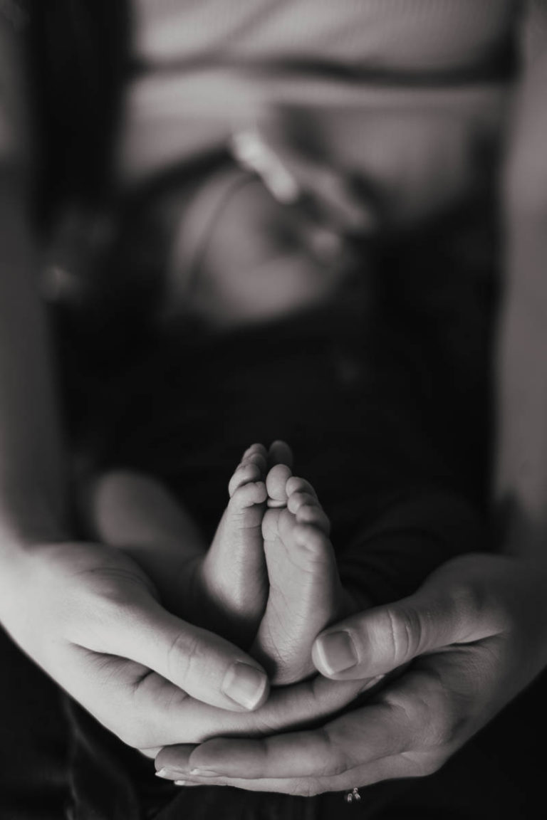 A newborn baby feet's cradled in her mother's hands.