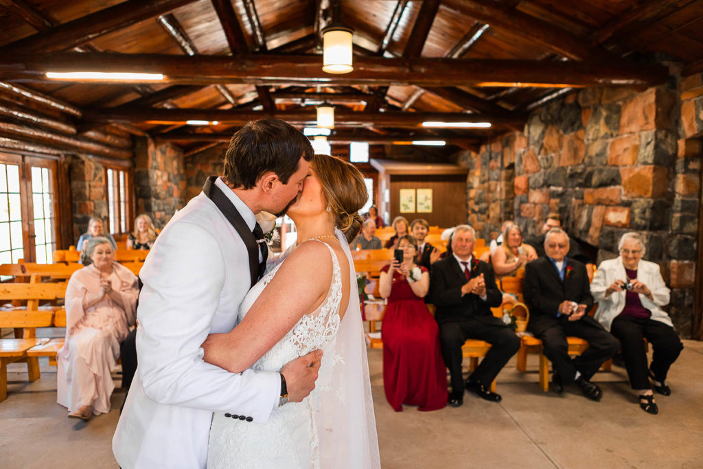 A couples first kiss during their wedding ceremony in Lady Slipper Lodge at Gooseberry Falls State Park