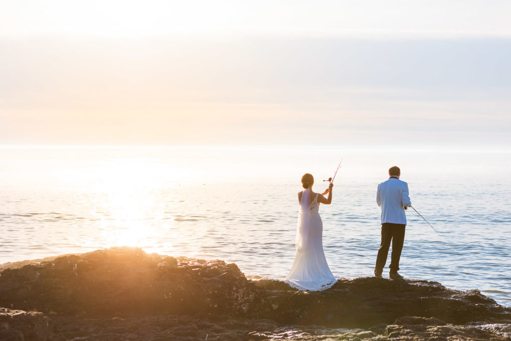 A couple fishes together in wedding clothes on their elopement day.