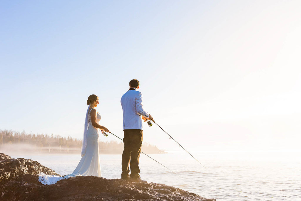 A couple fishes in their wedding clothes along the north shore during their elopement day.