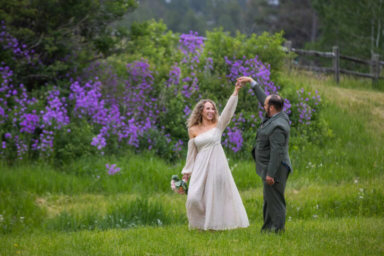 A couple dances in a field in front of purple wildflowers during their midwest elopement in the Black Hills of South Dakota.