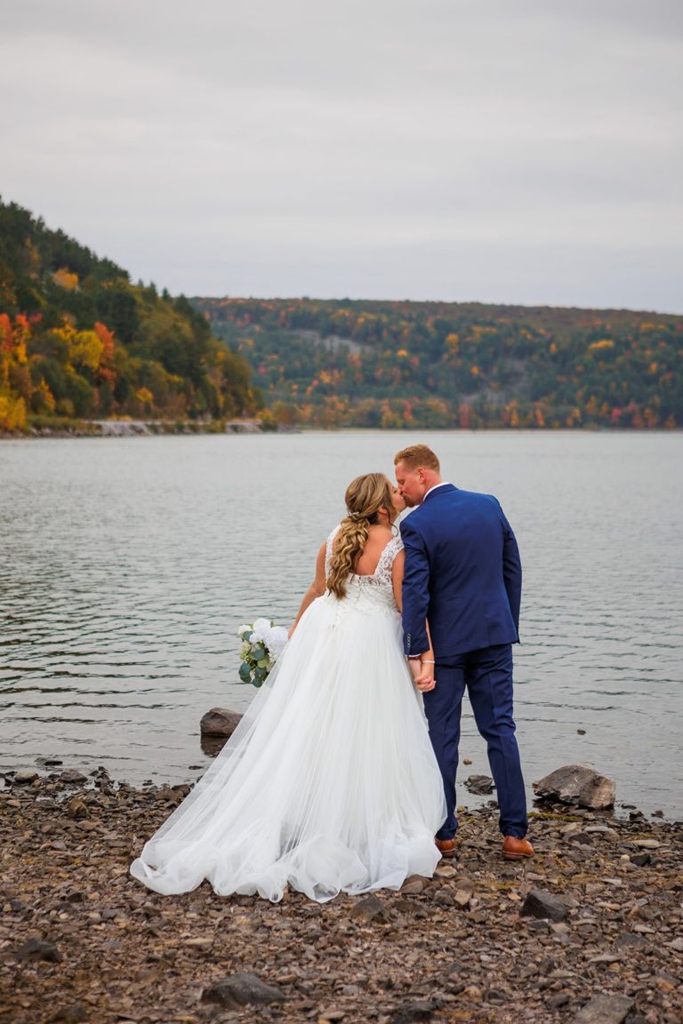 A newlywed kisses after their fall elopement at Devil's Lake. The fall colors are stunning in the background of this Devil's Lake elopement.