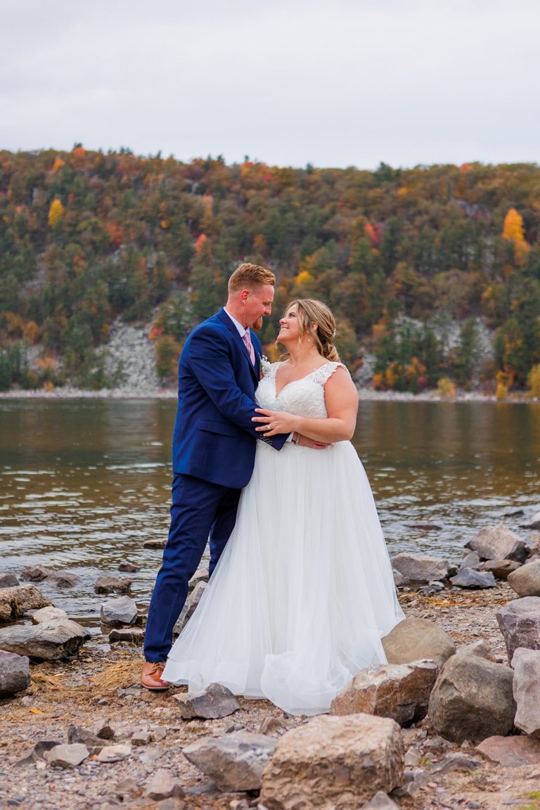 A couple embraces on the shore of Devil's Lake during their wedding. Devil's Lake State Park is one of the best places to elope in the Midwest!