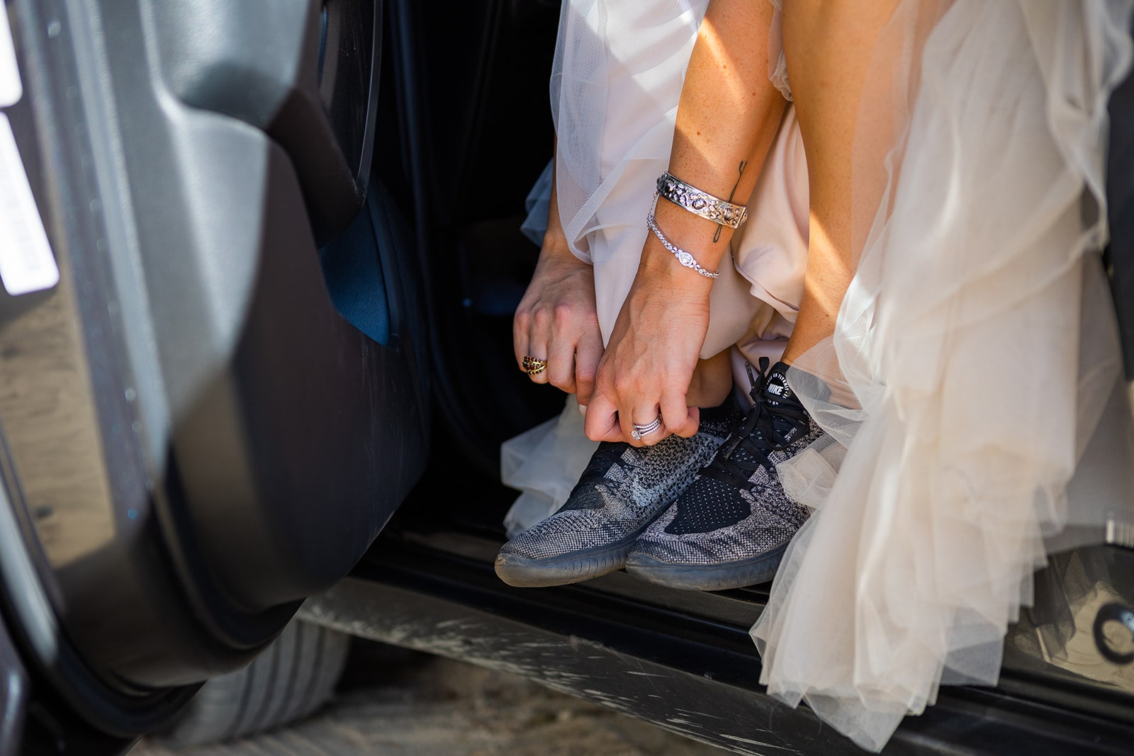 A bride ties her shoes while preparing to hike in her wedding dress for her adventure elopement.