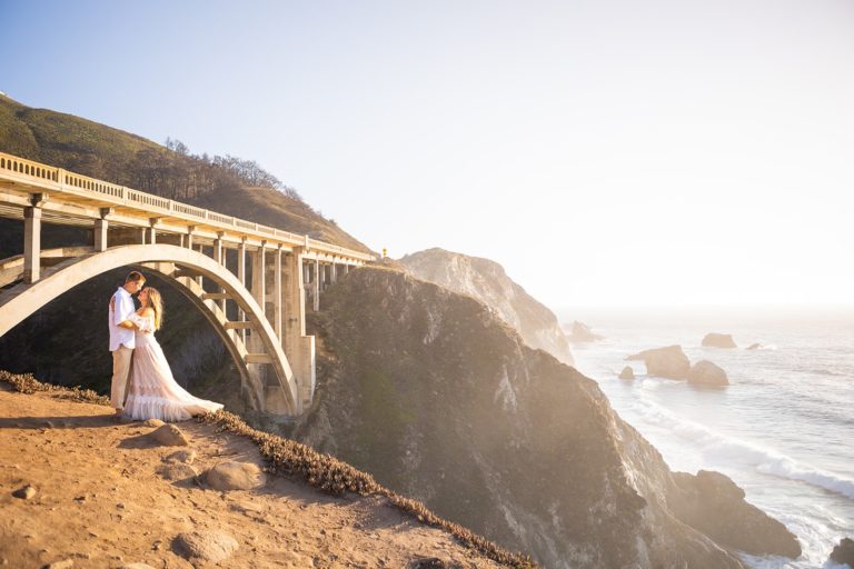 Taking a drive down the coast is a must for your Big Sur elopement! Here a couple embrace under one of the famous bridges along the coast of Big Sur.