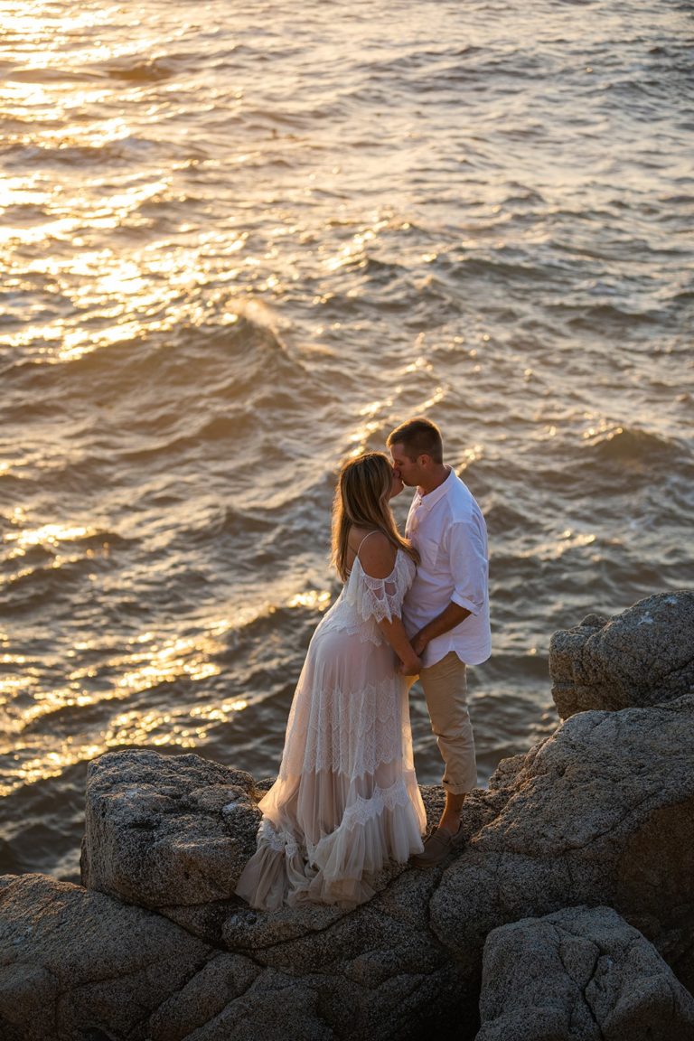 The golden light of sunset reflects off the ocean behind a couple as this kiss on their wedding day.