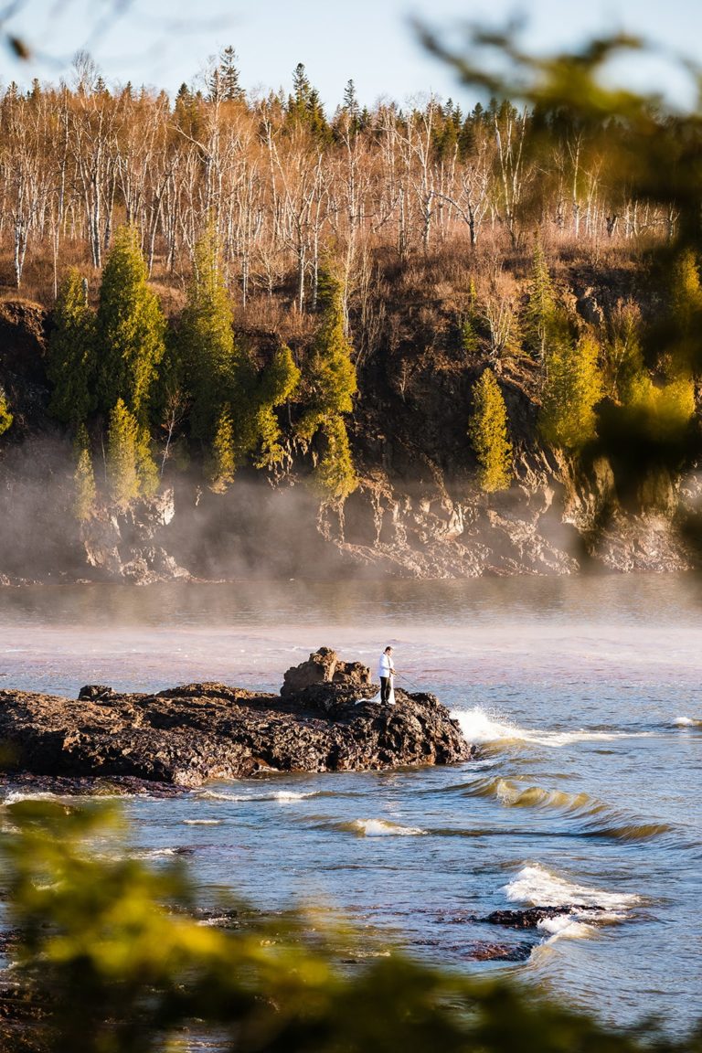 A newly married couple fish on the shore of Lake Superior during their Gooseberry elopement at Gooseberry Falls State Park in Minnesota.