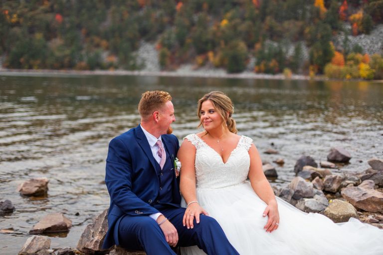 A couple soaks in those just married vibes as they sit on their shore of Devil's Lake after during their fall elopement.