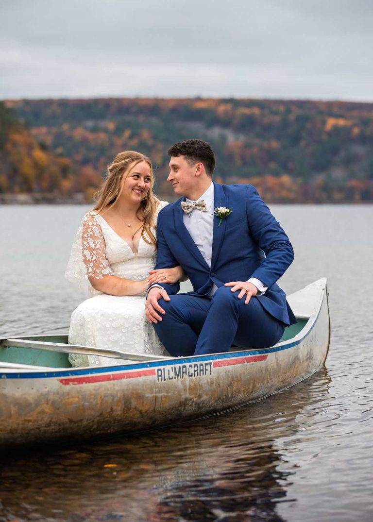 A couple smiles at one another while sitting in a canoe on Devil's Lake during their elopement. Devil's Lake State Park is one of the best places to elope in the Midwest!
