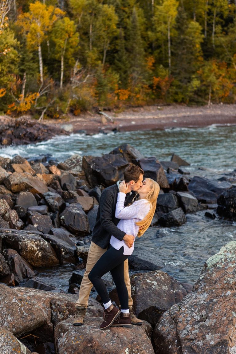 A newly engaged couple kisses along the rocky shore of Lake Superior during their North Shore engagement photo session.