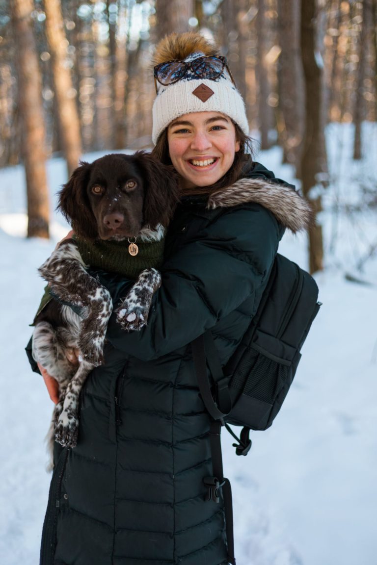 Tali, a Minnesota elopement and wedding photographer for Forever and Evergreens, smiles at the camera holding her dog, Lily Pad.