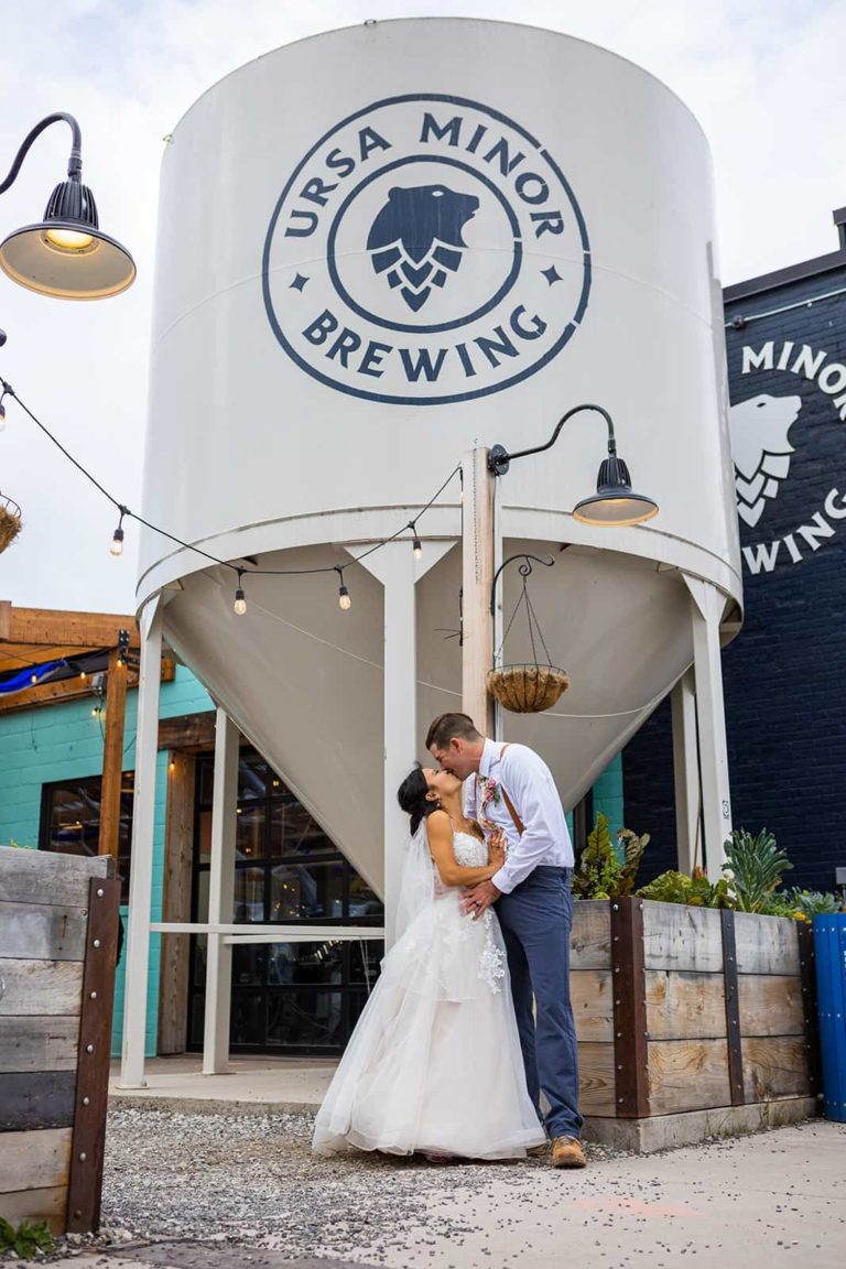 A couple kiss in front of Ursa Minor Brewing during their Duluth elopement.