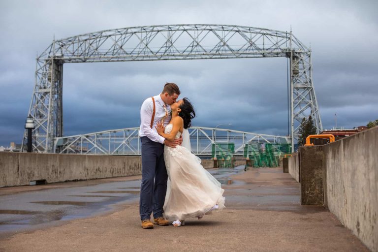 A bride and groom kiss below the Duluth Lift Bridge during their elopement in northern Minnesota.