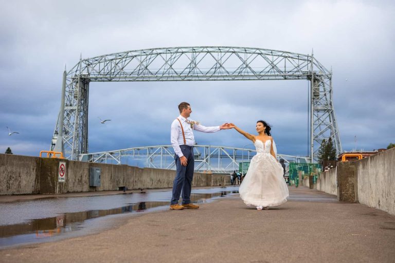 A bride and groom dance in front of the Duluth Lift Bridge during their fall elopement in northern Minnesota.