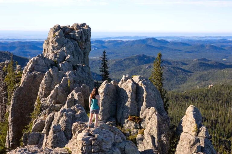 A woman stands on the rocky formations at the top of Black Elk Peak in the Black Hills National Forest.