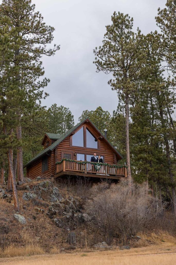 During their Hill City, SD elopement, a couple takes a moment to enjoy the scene from the balcony of their cabin tucked away in the Black Hills.