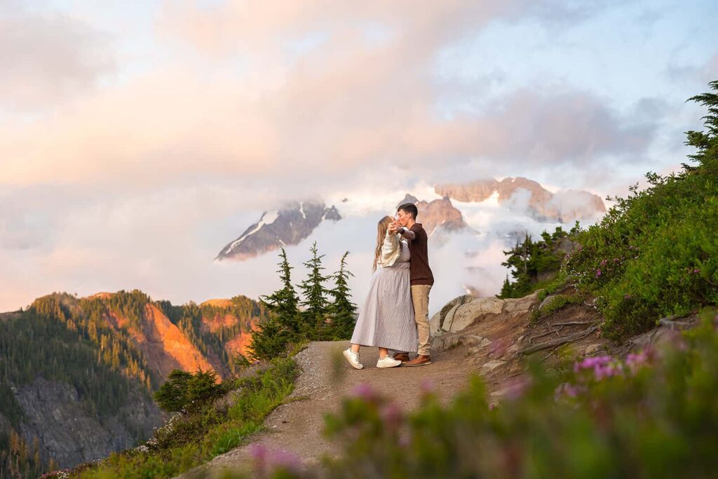 A couple share a kiss during a dance in front of Mount Shuksan while walking around Artist's Point in the Mount Baker ski area.