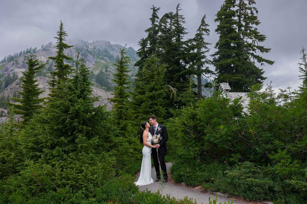 A bride and groom share a kiss among a grove of pine trees during their elopement in Washington state.