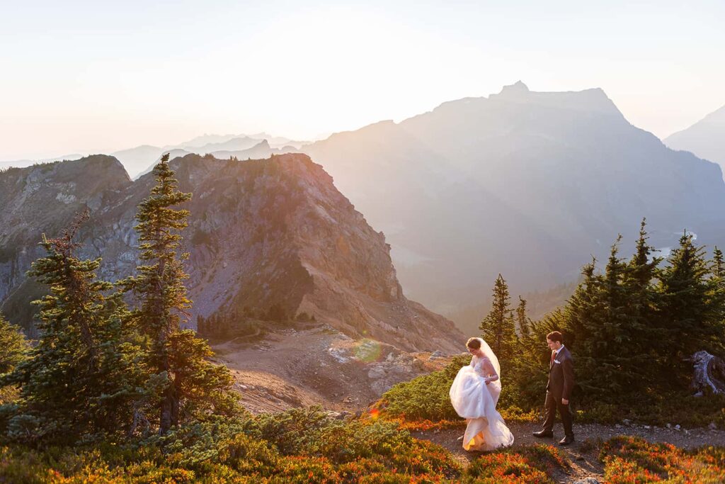 A bride and groom hike along a trail in the mountains during their Mount Baker Elopement in Washington state near Deming, WA.