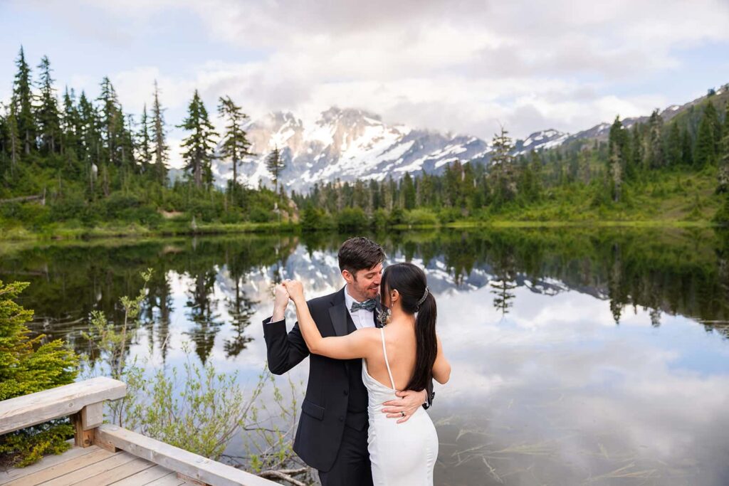 A bride and groom dance on the boardwalk in front of Picture Lake during their Mount Baker elopement.