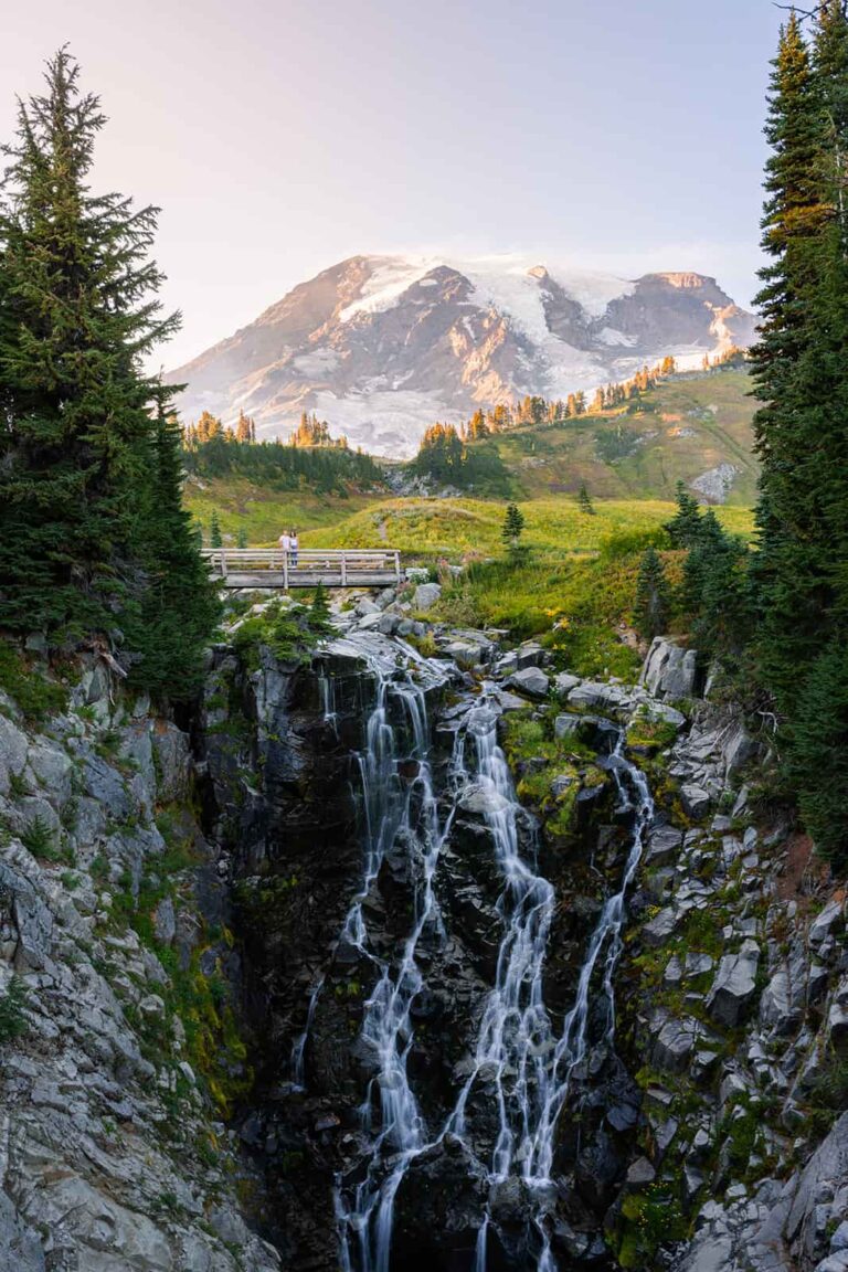 A couple stands on a bridge above a waterfall in the Paradise area of Mount Rainier National Park.