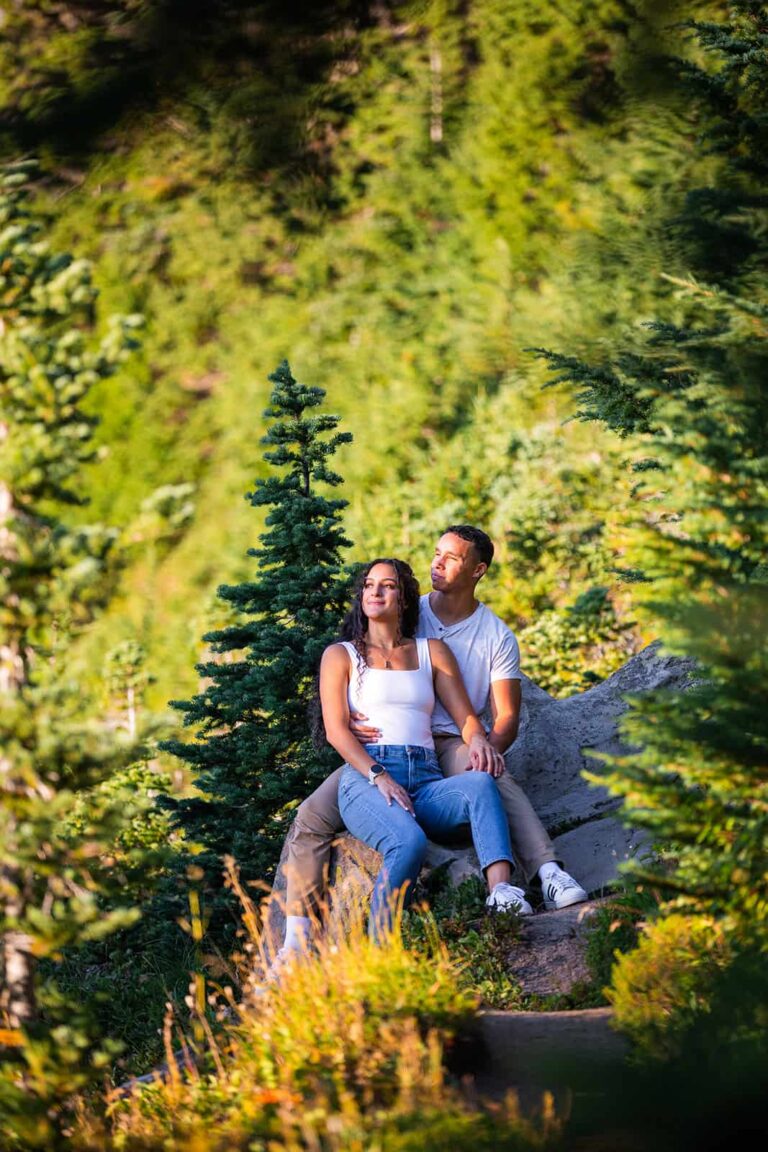 A young couple relaxes on a rock and stares off into the distance.