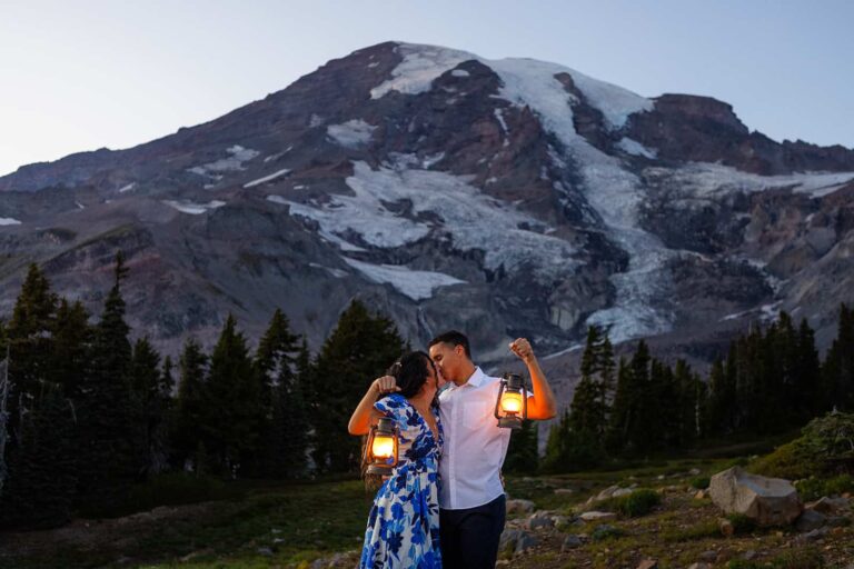 A couple kisses while holding lanterns in front of Mount Rainier.