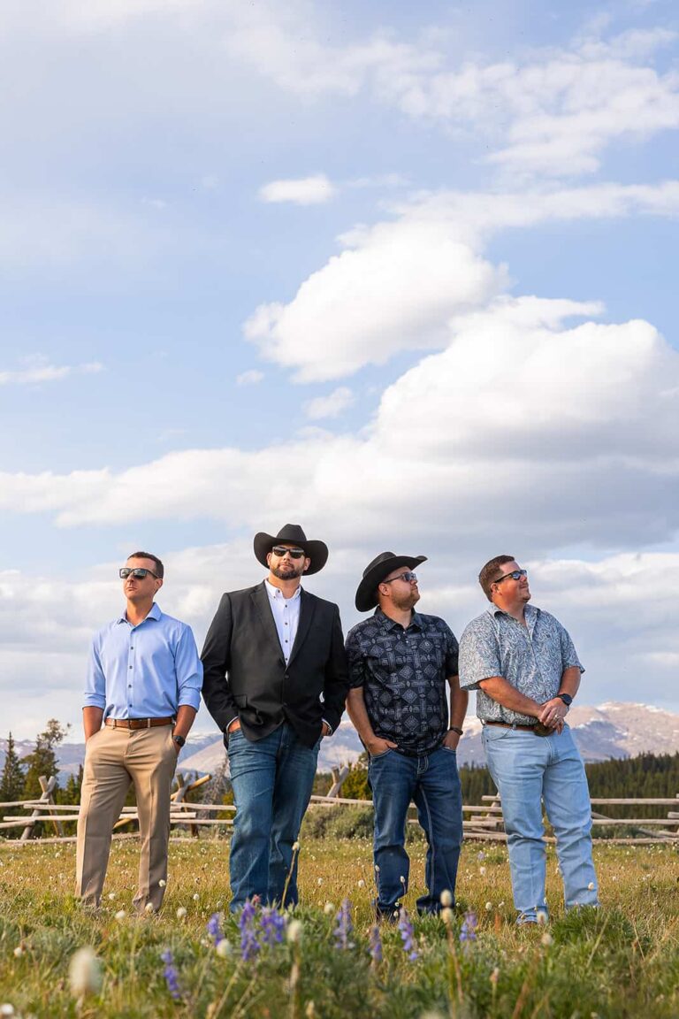 Four men pose for a photo in front of the mountains in Wyoming during a western style elopement.