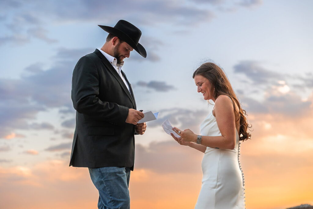 A couple reads private letters on a rocky overlook during sunset after their Meadowlark Lake Wedding in Wyoming.