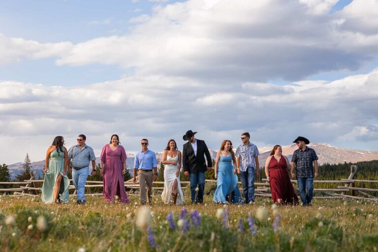 A group of friends wander through a meadow in front of a dramatic mountain view during a western-inspired elopement in Wyoming.