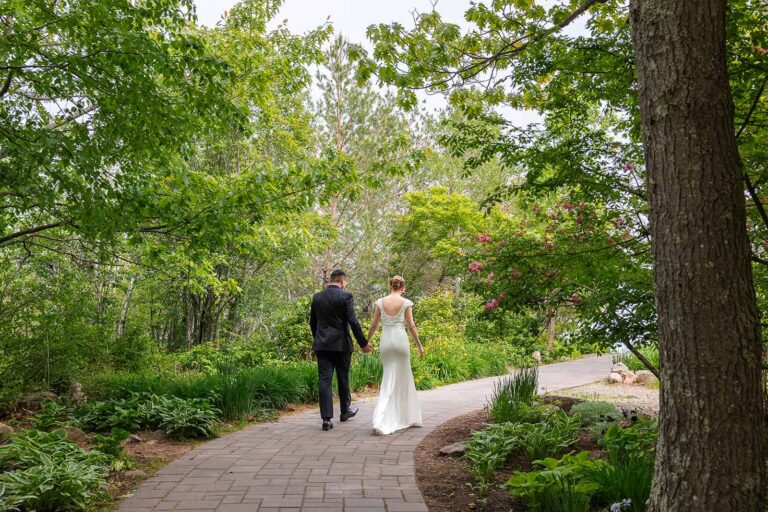 A couple stroll down a garden path on their wedding day.