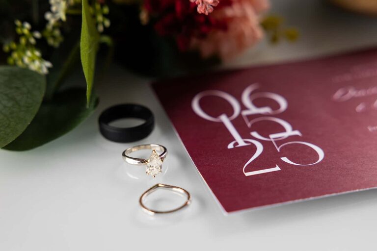 Detail photo of three wedding rings lined up beside an invitation.