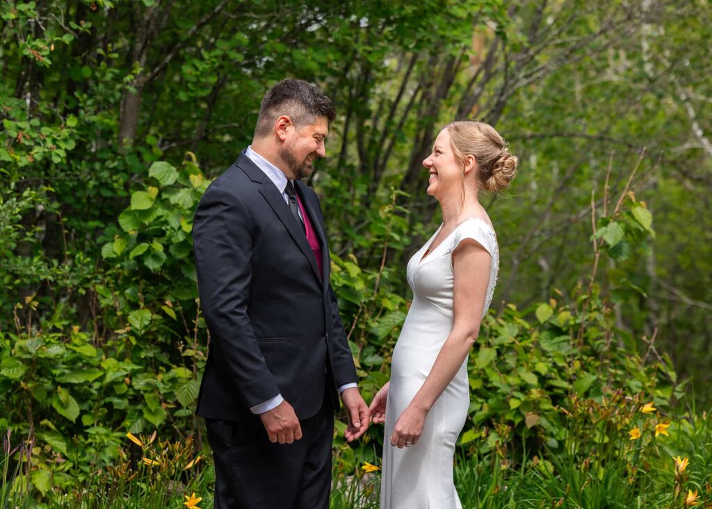 A couple share their "first look" on their wedding day against a beautiful garden backdrop.