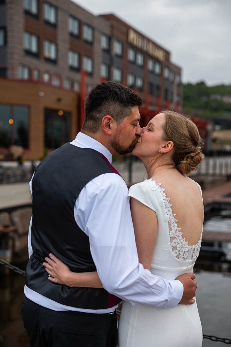 A couple in their wedding clothes share a kiss in front of Pier B during their wedding.