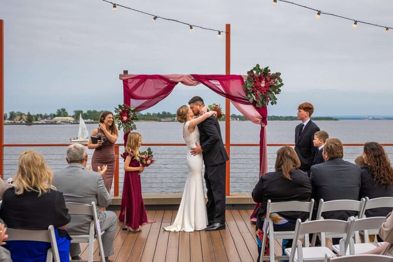 A couple shares their first kiss during their Pier B wedding on The Deck.