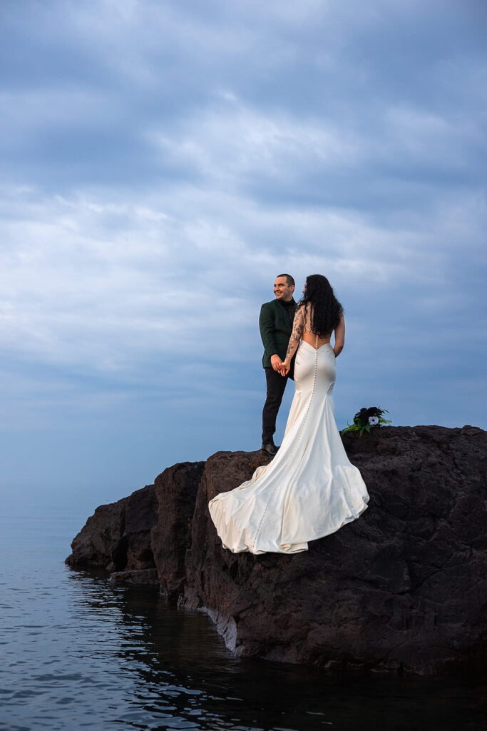A couple stand on the rocky shore of Lake Superior during their northern Minnesota elopement.