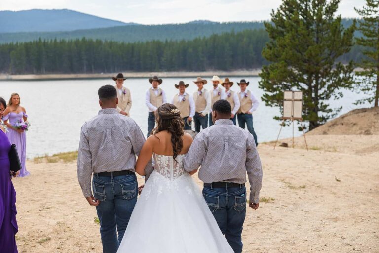A bride is walked down the aisle at her wedding by her two brothers.