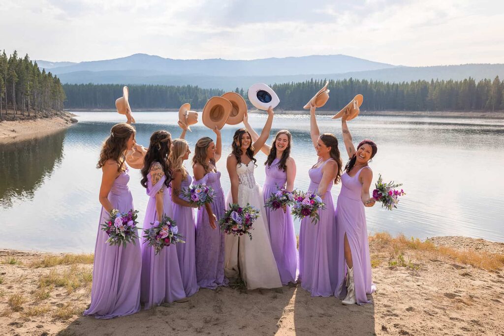 Bridesmaids in purple dresses lift their cowgirl hats and cheer during a Spear-O-Wigwam wedding.