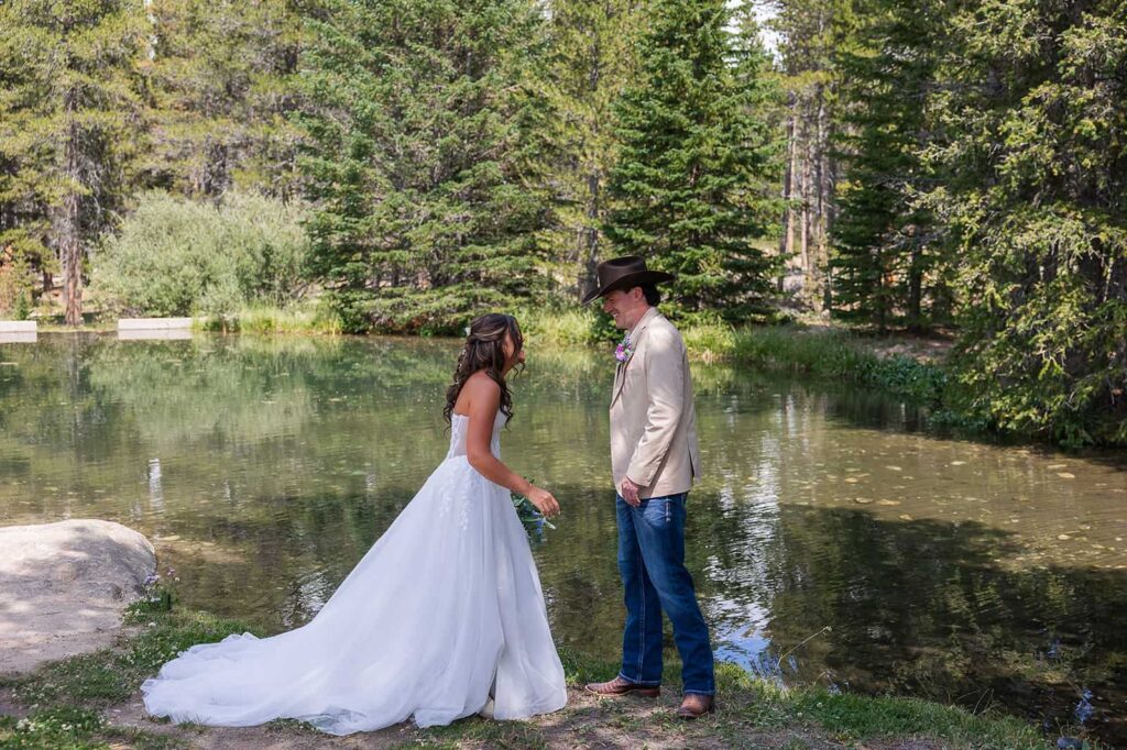 A bride and groom share their first look in front of the pond at Spear-O-Wigwam.