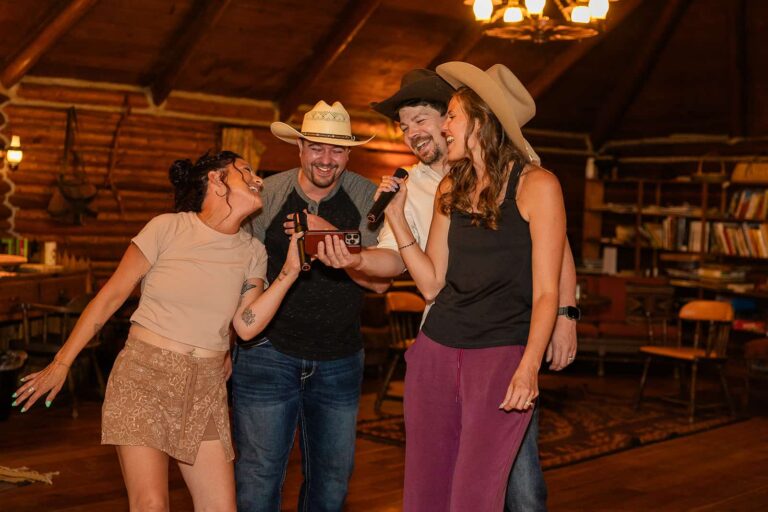 A group of people sing karaoke in the main lodge of Spear-O-Wigwam during a wedding reception.